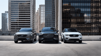 três carros da volvo parados em frente a varios edificios