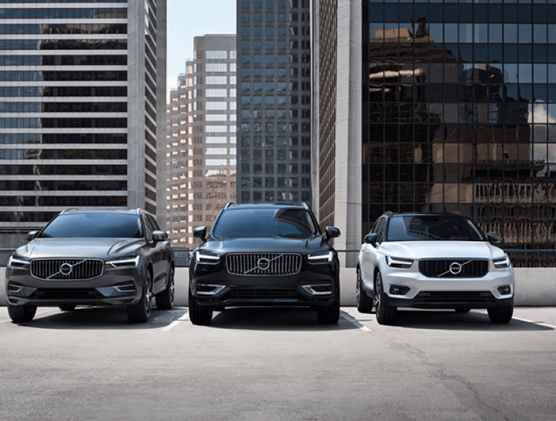 três carros da volvo parados em frente a varios edificios